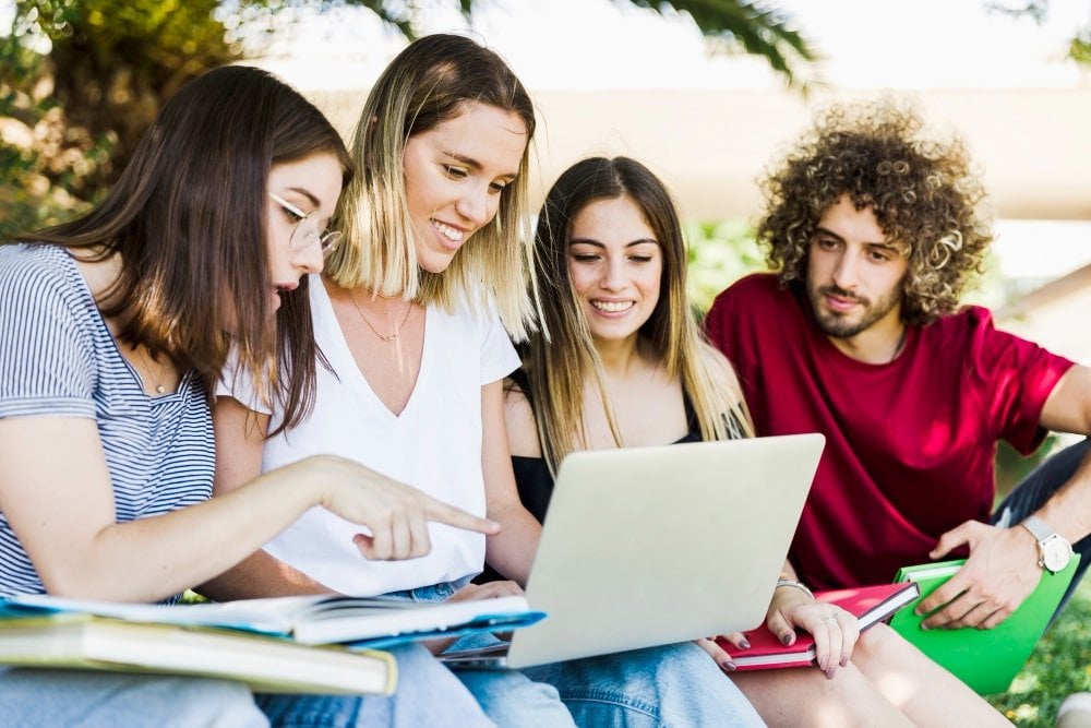 young-people-using-laptop-park-min
