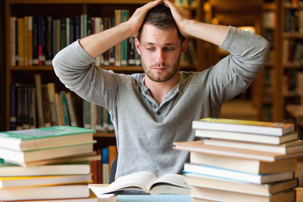 Tired student having too much to do in a library Tired student having too much to do in a library
